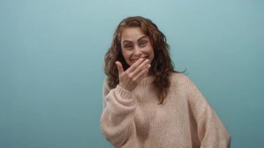 Mavi bir arka planda, rahat bir süveterle gülen bir kadın, neşe ve mutluluğu ifade ediyor..