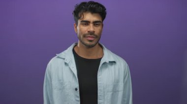 Kot gömlek giyen genç İspanyol adam mor arka plana karşı gözleri yükselterek kapatır; iç gözlem.