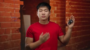 İnşaat alanında öpüşen genç bir adam, elinde anahtarlar, kırmızı gömlek, tuğla duvar zeminine yaslanmış, sanayi ortamında sevgisini ifade ediyor..