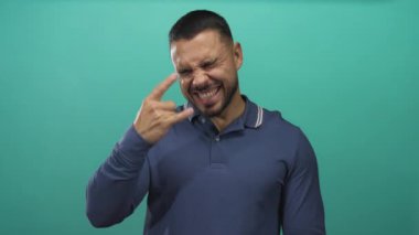 Kaya boynuzlarını gösteren bir adam stüdyoda canlı yeşil bir arka planı olan ağzı açık bağırıyor ve hareket ediyor..