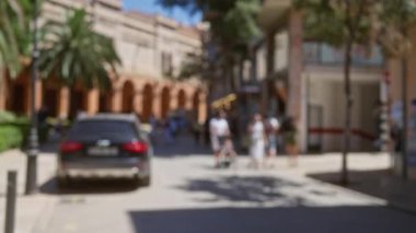 Mallorca 'daki bulanık arka plan, bir adamın bir kadının yanına bebek arabasını itmesi ve güneşli bir caddede park etmiş bir araba.