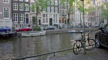 Amsterdam 'ın ikonik kanallarının ve bisikletlerinin bulanık görüntüsü. Parlak gün ışığında manzaralı su boyunca odaksız Hollandalı mimarisini yakalıyor..