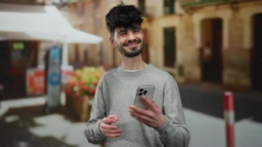 Güneşli bir şehir sokağında selfie çeken yakışıklı bir adam mutluluk ve karizma gösteriyor..