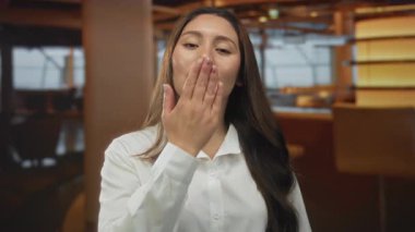 Kadın otel binasında el ele öpüşürken beyaz gömlek ve uzun saçlar giyer..