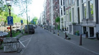 Şehrin şehir cazibesini vurgulayan klasik binalar ve park edilmiş bisikletlerle Amsterdam 'da bir caddenin bulanık görüntüsü.