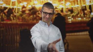 Gece karnavalında arka planda atlıkarınca ışıkları olan bir adam açık hava panayırında cazip bir atmosfer yaratıyor. Gece eğlencesi ve Kafkas dostluğu yakalıyor..