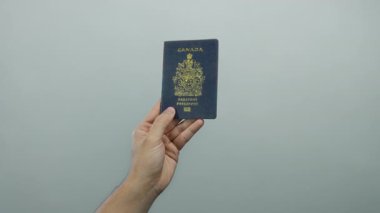 Beyaz arka plan karşısında Kanada pasaportu taşıyan adam, kimlik ve seyahat belgelerini gösteriyor, uluslararası hareketlilik ve vatandaşlık doğrulamasını vurguluyor.