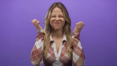 Ekose gömlek giyen bir kadın stüdyoda yumruklarını sıkar ve gözlerini sıkar..