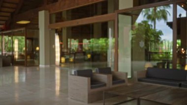 Bulanık lobi manzarası rahat oturma yeriyle lüks tatil köyü atmosferini yakalıyor, cam yansıtıcısıyla çözülmüş detayları vurguluyor, kapalı alan atmosferi yaratıyor..