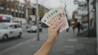 Şehir caddesinde elinde Arjantin pezosu olan bir adam açık şehir ortamında para gösteriyor..
