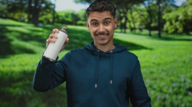 Güneşli bir günde parlak yeşil çimlerle dolu bir parkta sprey boya tutan genç İspanyol adam dışarıda rahat bir ortamda grafiti sanatıyla ilgili heyecanını dile getiriyor..