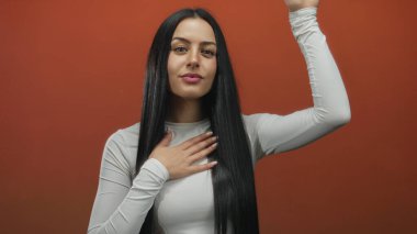 İspanyol kadın, portakal rengi arka planda el ele tutuşarak, özgüven ve samimiyet göstererek yemin ediyor..