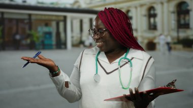 Şehir ortamında steteskopla gülümseyen kadın kendinden emin ve profesyonel görünüyor. Bu da sağlık ve günlük yaşam arasında bir bağlantı olduğunu gösteriyor..