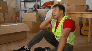 Yeni daireye taşınırken elinde karton kutularla oturan genç adam dinleniyor.