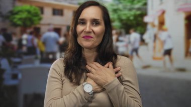 Genç İspanyol kadın ellerini açık terasta kalbe koyuyor..