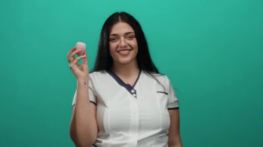 Elinde makyaj süngeri tutan kıvrımlı kadın yeşil arka planda gülümseyen güzellik ve kendine güven gösterisi yapıyor.