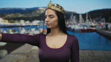 Taç giyen genç kadın, arka planda teknelerle limanda duruyor güneşli bir günde açık hava yaşam tarzını ve İspanyol güzelliğini ön plana çıkarıyor..
