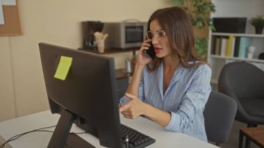 Ofis binasında masasında gözlük takan bir kadın bilgisayar ekranını işaret ediyor. Konsantrasyon.