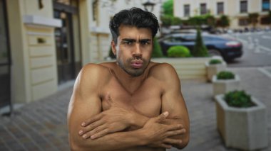 İnsan çıplak kaslı kollarını gösterir ve onları çenesinin altında sıkıca çaprazlar boş bir şehir caddesinde soğukta ürperirken; soğuk huzursuzluk.