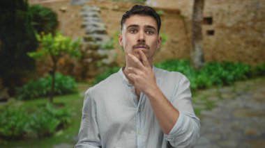 Açık hava parkında akıllı telefonlu genç bir adam. Yeşillik ve taştan yolların ortasında günlük giysiler içinde. Doğanın tadını çıkarırken..