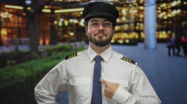 Kılavuz üniformalı genç adam, parlak şehir ışıklarının arasında liderlik sevinci ve kendine güvenini sergileyerek, geceleri kentte kendini güvenle gösteriyor..