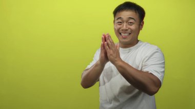 Stüdyoda canlı yeşil arka planla el çırpan adam; teşvik edici enerjiyi kutluyor.