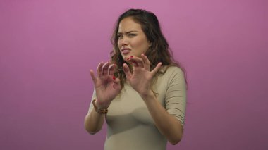 Pembe arka planda iğrendiğini ifade eden bir kadın, stüdyo ortamında güçlü bir duygusal tepkiyi gösteriyor ve genç İspanyol bir kadın onaylamıyor..