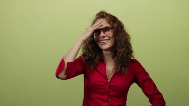 Alnında kırmızı tişörtle, sarı arka planda gülümseyen bir kadın arkadaşça bir ifadeyle neşe ve mutluluk saçıyor.