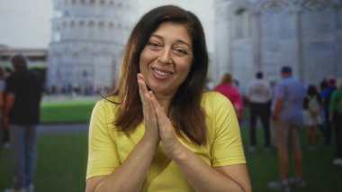 Kadın inşaat alanının önünde el sıkıştı, arkası görünen eğimli kule ve oradan geçen turistlerle; Hope Bellek Minnettarlığı.