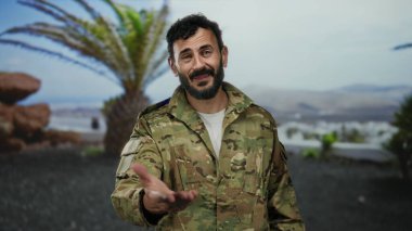 Askeri üniformalı İspanyol sakallı bir adam yemyeşil ve ağaçlarla dolu bir parkta dikiliyor..