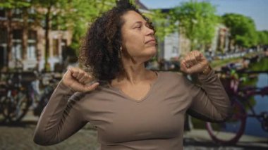 Orta yaşlı kadın çıplak kollarını ve ellerini sokakta başının arkasına uzatır; sabah yorgunluğu yorgunluğu uyuşukluğu.