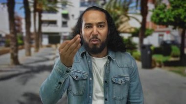 Erkek, palmiye ağaçları ve binalarla kaplı güneşli bir caddede somurturken burnunu sıkar ve alnına bastırır; rahatsız edici koku..