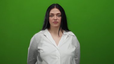 Beyaz gömlekli bir kadın canlı yeşil bir arka plana karşı duruyor, özgüven ve bireyselliği ifade ediyor, stüdyo ışıklarının altında onun artı boyutunu ve kıvrımlı figürünü vurguluyor..