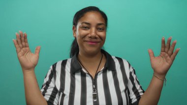 Hakem, stüdyoda siyah-beyaz çizgili forma ve ıslık ipi giyerek başının yanında el kaldırıyor..