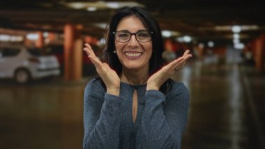 Yüzü halkalı gözlüklü bir kadın loş yeraltı otoparkında, neşeli bir sürpriz..