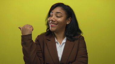 Sarı stüdyoda kahverengi ceketli ve beyaz gömlekli bir kadın parmak uçlarında geziyor..