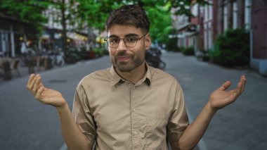 Genç İspanyol adam gözlüklü omuz silkiyor ve palmiyeler hareketli bir şehir caddesinde yukarı döndü; belirsizlik.