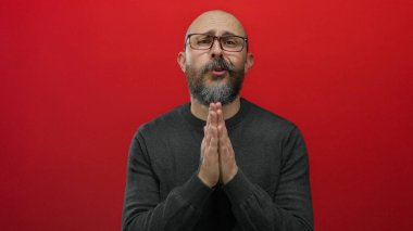 Kel, sakallı ve gözlüklü bir adam koyu renk bir süveter giyer ve stüdyoya kapanır..