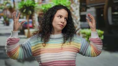 Canlı bir caddede renkli bir kazak giymiş, açık havada canlı iletişim kuran bir kadın..