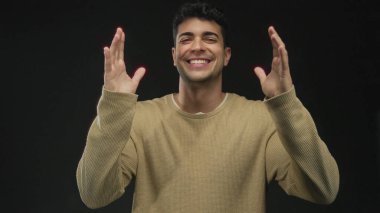 Erkekler el ele tutuşup, onları arka plana doğru kaldırıyor. Genç İspanyol erkek gülümsüyor ve siyah uzayı çerçeveliyor..