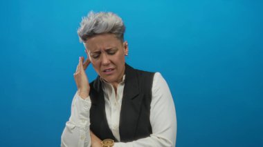 Kadın gergin bir hareketle elini başına bastırarak, kapalı gözleri ve çatık kaşları ile tapınağa dokunur;.