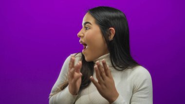 Şaşırdığını ifade eden bir kadın canlı mor arka plana karşı ağzı ve elleri açık, coşkulu ve genç bir enerji sergiliyor..