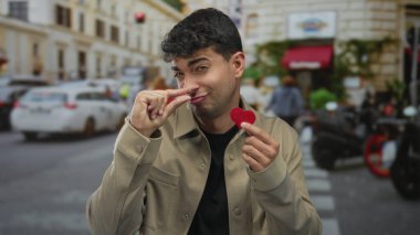 Adam şehir caddesinde küçük bir kalp göstermek için parmaklarını çimdikler; oyuncu sevgi.
