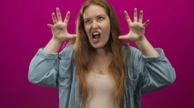 Çıplak dişli bir kadın pembe stüdyoda ellerini kaldırarak homurdanıyor..