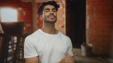 Genç İspanyol adam göğsüne kadar iniyor ve elleri bitmemiş inşaat işinde, kendine güveni tam..