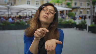 Avuç içli bir kadın, şehir binasının önündeki bir restoranın terasında dua jestinde birbirine bastırılmış..