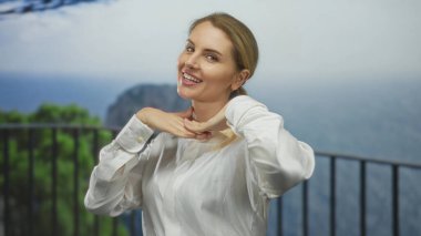 Doğada, okyanus manzaralı, beyaz gömlekli, neşeli, neşeli ifadeyi kucaklayan, mutluluğu ve özgürlüğü yakalayan, genç, sarışın, neşeli, gündüz manzaralı bir kadın..