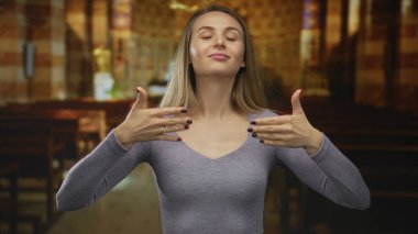 Kilisede elleri havada, huzurlu bir ortamda dinginlik ve dinginlik ve dinginlik sergiliyor. Ilık, huzur ve sükuneti ifade ediyor..