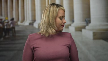 Genç kadın kollarını kaldırıyor ve süslemeli antik sütun binasına karşı avuçlarını açıyor; saf neşe.