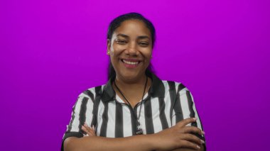 Hakem kadın, bir stüdyoda canlı mor bir arkaplan karşısında kollarını kavuşturarak güvenle gülümsüyor..